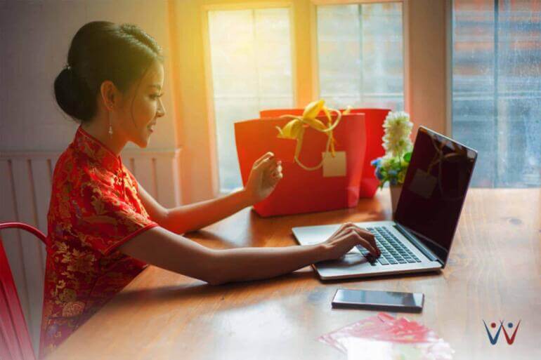 wanita tionghoa memakai Cheongsam mengerjakan strategi marketing tahun baru imlek di depan laptop